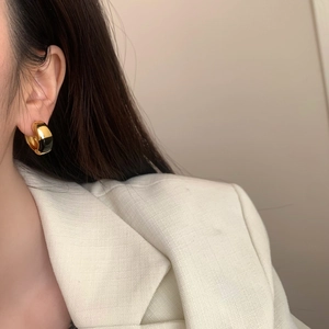 Close-up of minimalist gold hoop earrings with black enamel drip detail on female model