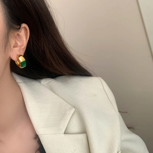 Gros plan de boucles d'oreilles créoles dorées vintage avec finition en émail vert