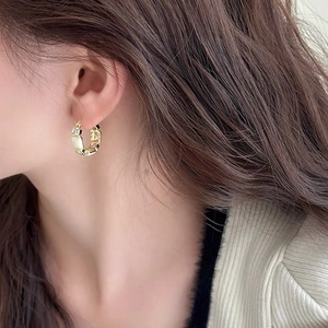Elegant gold hoop earrings with white stones and crystals on a model's ear
