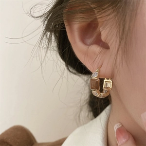 French vintage C-shaped gold hoop earrings with brown resin and zircon stones on a model