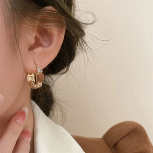 French vintage gold earrings with brown enamel and zircon stones worn by a model