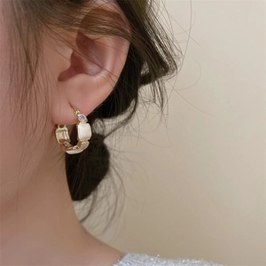 Detailed view of French vintage gold hoop earrings with white enamel and zircons