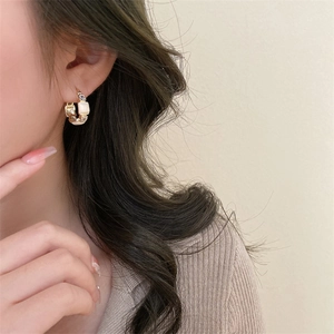 Detail of vintage gold earrings with white stone inlay and zircon crystals on model