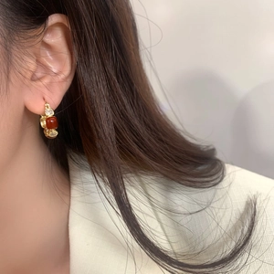 Close-up of elegant gold hoop earring with brown zircon and small crystals on a model