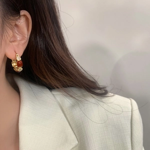 Close-up of elegant gold hoop earrings with amber resin and sparkling zircon stones