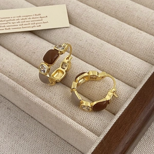 Detail of gold-plated hoop earrings with brown enamel and zircons in a velvet box