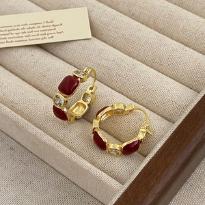 Detailed view of vintage gold earrings with red enamel and sparkling zircons