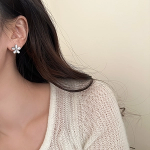 Vue rapprochée de boucles d'oreilles fleur en œil de chat et zircon portées par un mannequin