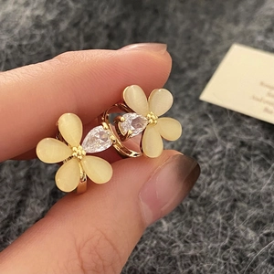 Gros plan de boucles d'oreilles fleur en plaqué or avec pétales œil de chat et zircon