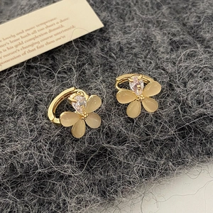 Détail de boucles d'oreilles fleurs en oeil-de-chat avec zircon sur texture laine