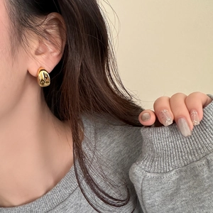 Polished gold drop earrings shown on model, featuring a smooth minimalist mirror finish
