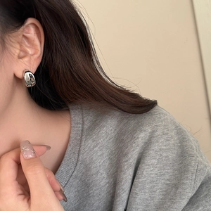 Close-up of minimalist silver geometric teardrop earring worn on model's ear