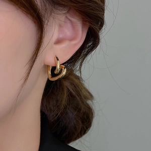 Elegant gold heart-shaped hoop earrings with a high-polish mirror finish on a model