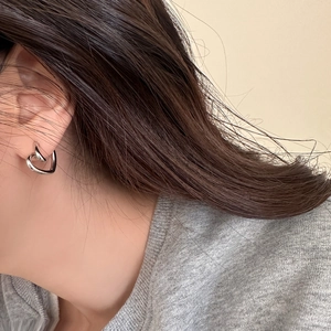Close-up of heart-shaped overlapping silver earrings worn by a model in a minimal style