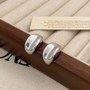 Macro shot of polished silver bean earrings on vintage velvet display box for women