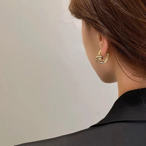Polished gold heart-shaped twist earrings worn by model for an elegant minimalist look