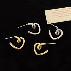 Minimalist silver and gold heart stud earrings shown on an elegant black velvet surface