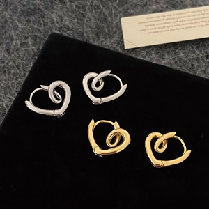 Minimalist heart twist hoop earrings in silver and gold displayed on a black velvet mat