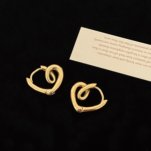 Macro shot of gold heart-shaped twisted hoop earrings on black velvet background