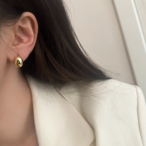 Boucles d'oreilles minimalistes dorées en forme de goutte portées par un mannequin