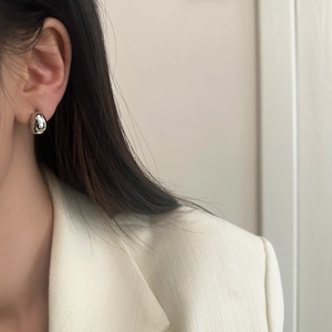 Gros plan de boucles d'oreilles gouttes argentées minimalistes portées par un modèle
