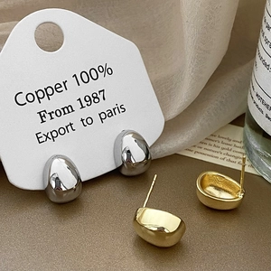 Gros plan de boucles d'oreilles goutte en or et argent faites de cuivre pur à 100 %