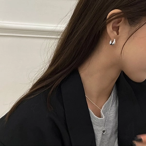 Minimalist silver geometric twist drop earrings and heart pendant necklace on model