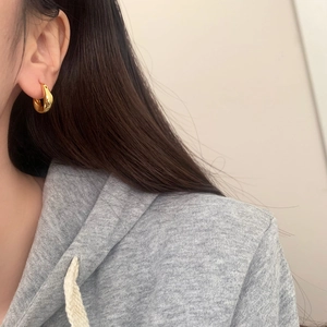 Detail of elegant gold twisted teardrop earrings with a polished geometric metallic finish