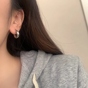 Close-up of a silver teardrop earring with a polished mirror finish on a female model