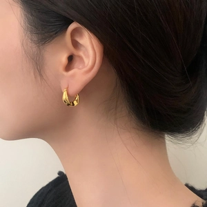 Close-up of elegant chunky gold hoop earrings with a twisted metallic texture on a model