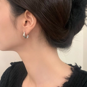 Detailed close-up of geometric silver hoop earring on model showing sleek metallic luster
