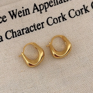 Macro view of gold U-shaped geometric earrings on canvas showing the polished metal finish