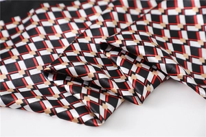 Close-up of geometric pattern silk scarf with red lines and gold diamond accents