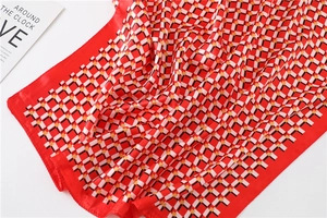 Detailed macro view of the silky red geometric plaid scarf with smooth texture and hemmed edges