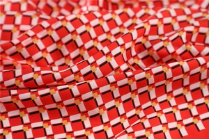 Macro shot of smooth satin scarf with red and white geometric checkered patterns