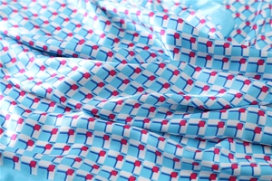 Macro view showing the smooth texture and vibrant blue geometric patterns of the silk scarf