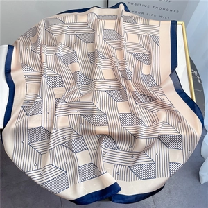 Elegant geometric stripe silk scarf shawl in beige and navy blue on marble surface