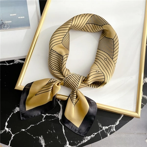 Striped geometric silk scarf in yellow and black, folded on a marble background