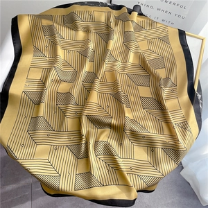 Close-up of silky geometric striped square scarf with golden finish on marble table