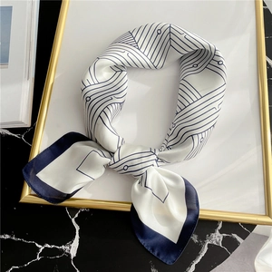 Silk scarf with geometric blue patterns on creamy white base over black marble