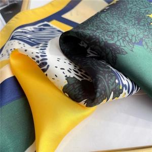 Close-up of printed silk scarf with artistic yellow, green, and blue geometric patterns