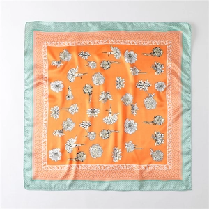 Close-up of elegant silk scarf showing vibrant orange floral print and mint green plaid border