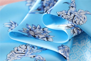 Macro detail of glossy light blue satin scarf featuring elegant floral patterns