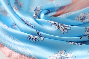 Close-up of sky blue floral silk scarf showing smooth satin texture and pink plaid edge