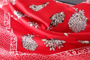 Detailed macro view of red silk scarf with elegant white floral patterns and ornate border