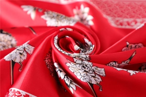 Macro shot of red floral silk scarf showing premium satin texture and draped fabric folds