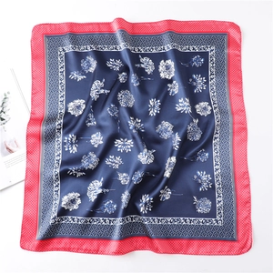 Detailed close-up of navy blue floral silk scarf with red diamond check border