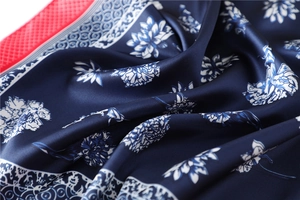 Detail of dark blue silk scarf featuring white floral prints and geometric borders