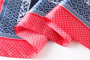 Macro detail of silk scarf showing navy floral patterns and red checkered borders