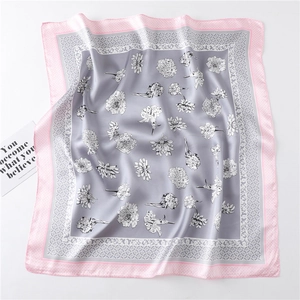 Detailed macro view of soft gray silk scarf with white floral patterns and pink border